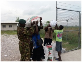 These Les Cayes residents get some help from members of the CARICOM contingent in lifting the family packages.